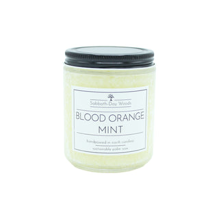 Blood Orange Mint scented palm wax candle in clear glass jar with black lid.