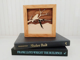 Bird on a Branch - Walnut & Maple, handcrafted cherry wooden square Box Clock with Bird on a Branch design in maple over a walnut background. On a stack of books.