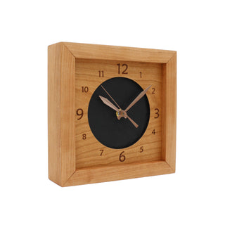 Leather & Cherry, handcrafted cherry wooden box clock featuring a numbered cherry face with cutout revealing black leather circle in the center. Angle View.