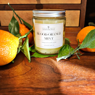 Blood Orange Mint scented palm wax candle in clear jar with fresh oranges.