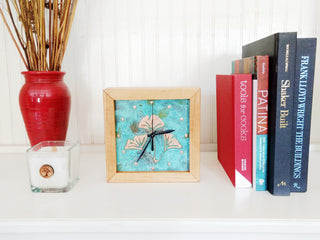Square Clock framed with cherry wood and patina copper face with ginkgo design on a shelf with books