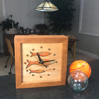 Fish at School, handcrafted cherry wooden Box Clock with fish design in maple over a orange background. Pictured with glass spheres.