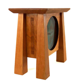 Side view: Cherry wood mantel clock with four tapered legs, patina copper face and pendulum.
