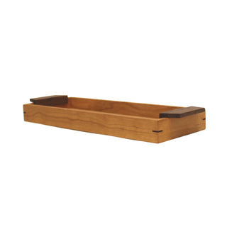 Angle view: narrow rectangular cherry wood tray with 1.75" sides and walnut handles on both ends.